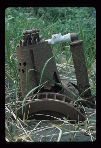 Photo of auto part in sand and grass.