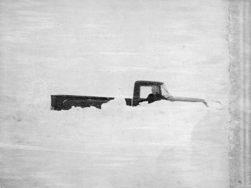 Photo of man and pickup truck in deep snow.