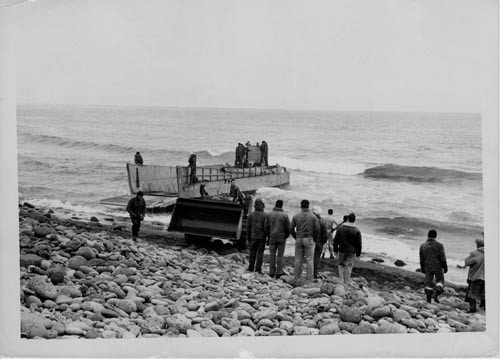 Photo of people on rocky beach landing craft.