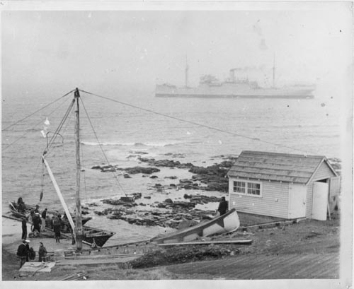 Photo of men on a dock with a ship in the background.
