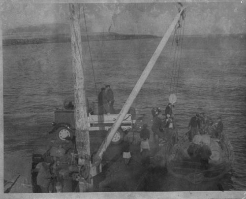 Photo of men unloading baidar using a wooden crane at the St. George dock.