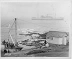 Thumbnail photo of men on a dock with a ship in the background.