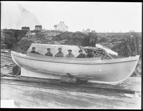 Photo of five men and small boat.