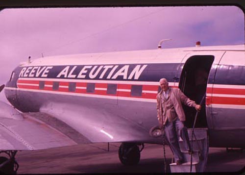 Photo of arrival of man descending from ramp of Reeve Aleutian Airplane.