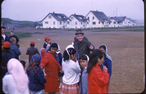 Photo of children gathering around older man.