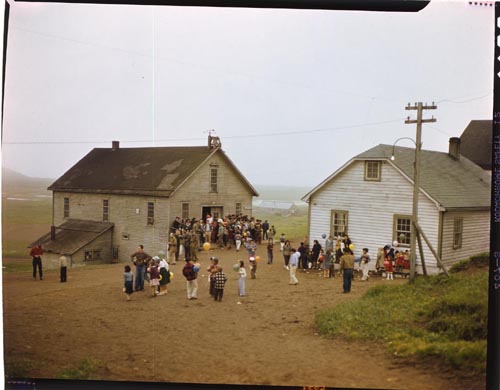 Photo of a large group of people outside of two buildings.
