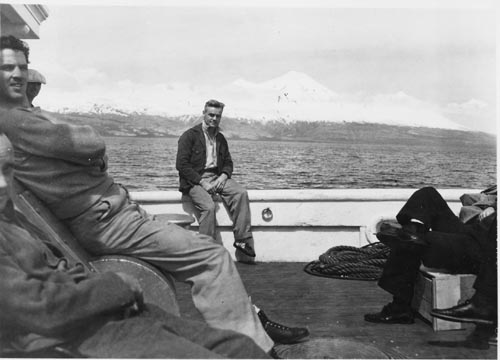 Photo of Victor Scheffer sitting on the railing of the ship U.S.F.S. Penguin.