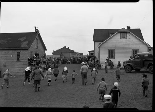Photo of a large group of people standing by buildings at a fourth of July celebration.