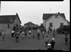 Thumbnail photo of a large group of people standing by buildings at a fourth of July celebration.