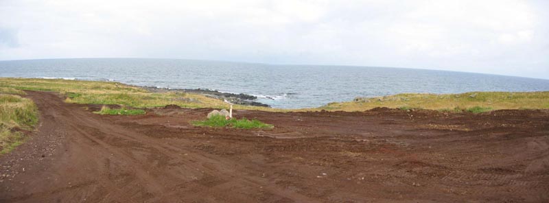 Photo of dirt road and bare earth near shore at the Inactive Gas Tank Farm, after completion of environmental remediation.