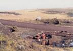 Thumbnail photo of piles of rusted oil drums alongside a dirt road at the Oil Drum Dump Site.