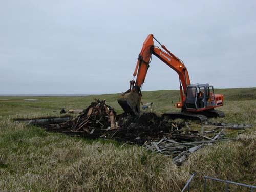 Photo of an excavator removing wooden debris at the Aleut Bunkhouse.