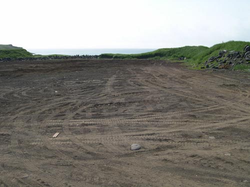 Photo of an expanse of bare earth showing the petroleum contaminated soil stockpile location at the Blubber Dump after remediation.