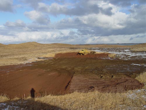 Photo of environmental remediation at the Vehicle Boneyard showing a wide expanse of bare earth in a dry grassy area.