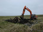 Thumbnail photo of an excavator removing wooden debris at the Aleut Bunkhouse.