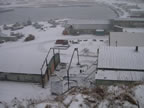 Thumbnail photo of view of the Tract 46 Sheet Metal Garage after demolition showing an empty space between snow covered buildings.