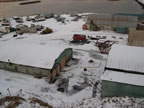 Thumbnail photo of view of the Tract 46 Sheet Metal Garage from Village Hill after demolition showing snow covered buildings, equipment, and boats.