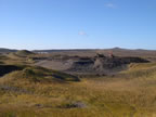 Thumbnail photo of view of the petroleum contaminated soil stockpile in Cell C of the St. Paul Landfill showing an expanse of dry grass with heavy equipment on a dirt area in the background.