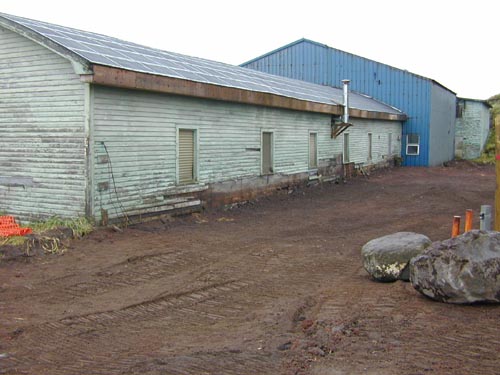 Photo of a bare area near a weathered blue building.