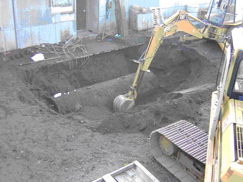 Photo of an excavator digging a hole around a partially buried cylinder.