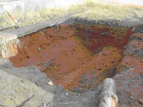 Photo of a hole in the ground filled with orange soil.