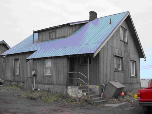 Photo of a gray building with a blue roof.