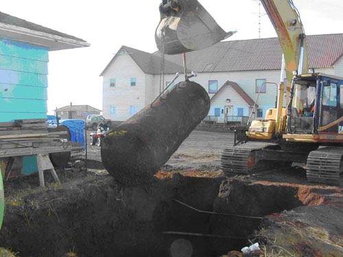 Photo of an excavator lifting cylinder out of a hole in the ground.