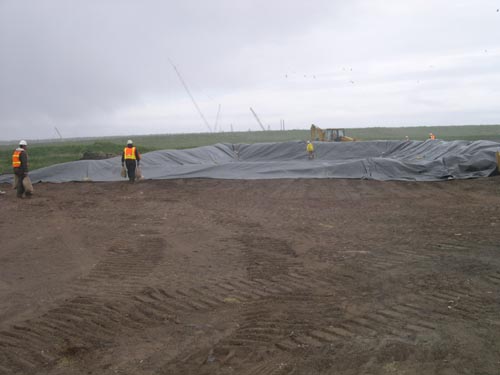 Photo of a large tarp being placed and weighed down.