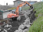 Thumbnail photo of an excavator placing boulder-sized rocks at the base of a hill.