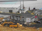 Thumbnail photo of two buildings near water surrounded by construction material and equipment.