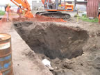 Thumbnail photo of a large hole with heavy equipment in the background.