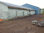 Thumbnail photo of a bare area near a weathered blue building.
