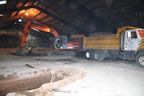 Thumbnail photo of interior of a large building with an excavator digging hole.