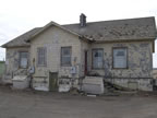 Thumbnail photo of weathered yellow buildings.