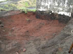 Thumbnail photo of shallow hole with red soil.
