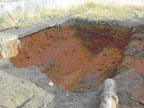 Thumbnail photo of a hole in the ground filled with orange soil.