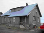 Thumbnail photo of a gray building with a blue roof.