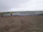 Thumbnail photo of a large tarp being placed and weighed down.