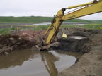 Thumbnail photo of excavator digging in a hole filled with water.