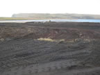 Thumbnail photo of large expanse of bare earth with heavy machinery tracks.