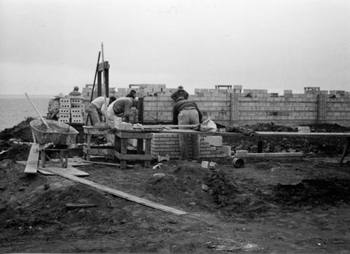 Photo of men working with concrete blocks at construction site.