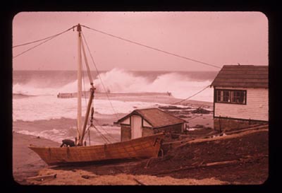 Photo of boat on beach with heavy surf near dock winch and pump houses.