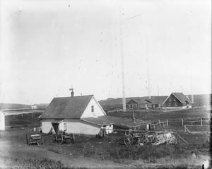Photo of white barn surrounded by farm equipment.