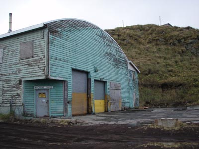 Photo of the machine shop, a geen building with a curved roof.