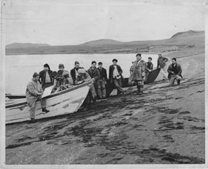 Photo of a group of men on shore with a boat.